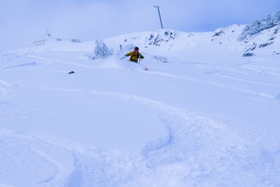 人的黄色外套骑在雪董事会在冰雪覆盖的地面白天
